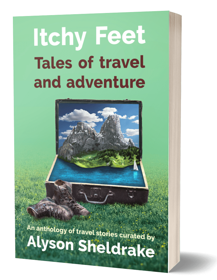 The cover of "Itchy Feet: Tales of Travel and Adventure". The cover is green and shows an old-fashioned open suitcase sitting open on the grass with a pair of hiking boots next to it.. Inside the suitcase is an island surrounded by ocean under a blue sky with clouds.