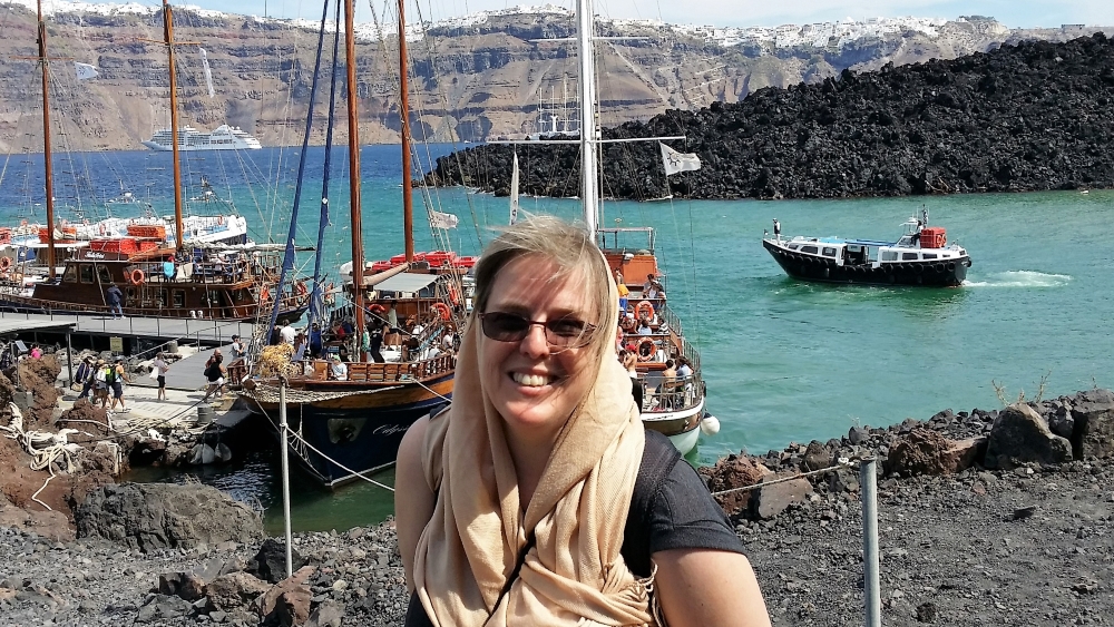 Photograph of the author in the centre of Santorini's caldera - there are small boats in the background.
